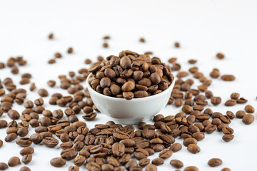 Roasted coffee beans in ceramic bowl on white, close-up