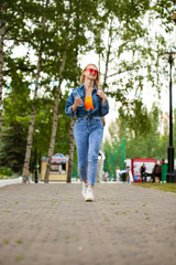 Fototapeta premium Young Blonde woman in blue jeans walking in summer park