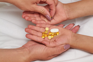 Hands with pills. Woman's hand puts tablets in child's hand.