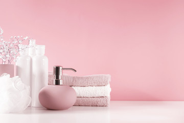 Soft light bathroom decor in pastel pink color, towel, soap dispenser, white flowers, accessories on pastel pink shelf. Elegant decor bathroom interior.