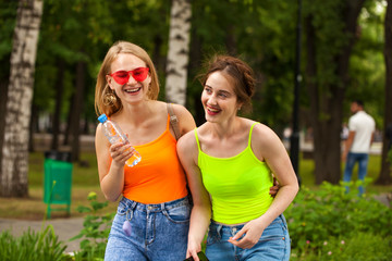Obraz premium Two girlfriends walking on summer park, outdoors
