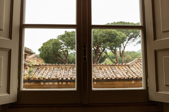 roof and green trees behind window in rome, italy