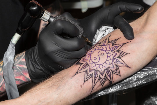 Tattoo in form of circular pattern on man's arm