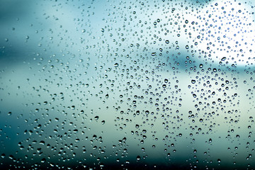 Naklejka na ściany i meble Rain drops in raining day on window car with street Bokeh Light Out Of Focus, City nightlife in rainy season.Water drop on the glass,abstract background.