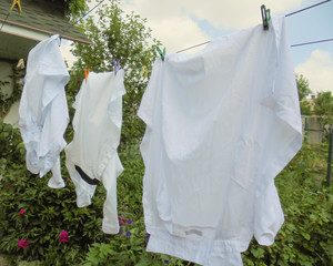children's white shirts hang on a rope in the yard and dry