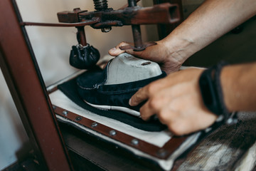 Close up shot of old shoemaker in his store. Traditional way of shoe making process.