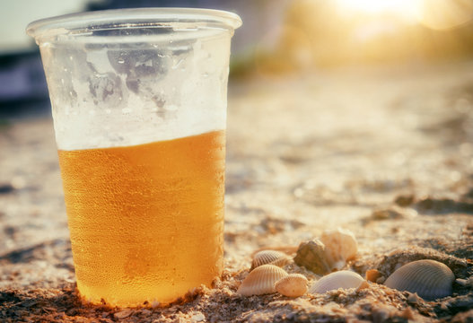 Cold beer on beach sand with seashells party summer beach sunset