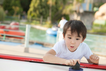Joyful asian child boy playing air hockey outdoors. Family sporting events in the park.