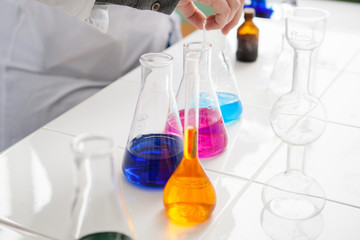 girl lab technician mixes  liquids in flasks