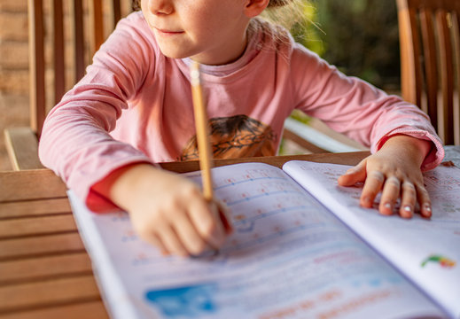 Studente femmina bambina mani su quaderno di scuola per fare i compiti delle vacanze pensando a divertirsi