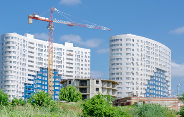 Fototapeta na wymiar Round house under construction on the background of new white buildings and blue sky.