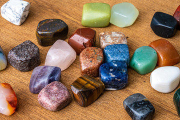 Collection of different colored polished gemstones an jewels luxury on wooden underground