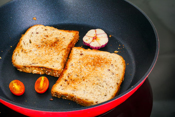 Roast toasts with garlic and tomatoes in fry pan