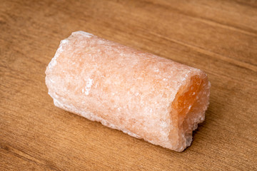 Salt crystal drill probe containing minerals causing its pink color on wooden underground