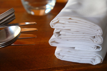 close up of knives, forks and spoon with napkins on a restaurant table