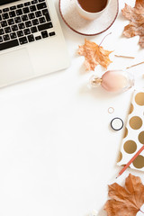 Autumn composition on desk with laptop, mug of coffee, cosmetics and accessories on white background