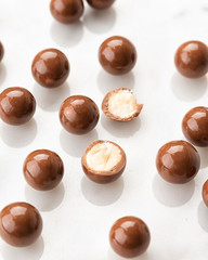 Exclusive handcrafted chocolate candy with nut. Luxury handmade bonbon on white marble background. Product concept for chocolatier