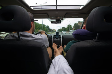 woman sitting at backseats of car put legs on armrest sunroof