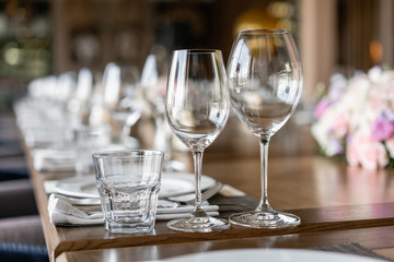 Wine glasses in the foreground. Wedding Banquet or gala dinner. The chairs and table for guests,...