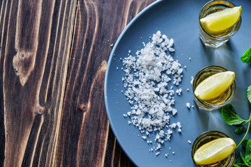 Tequila shot with lime and sea salt on grey plate