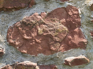 Red sandstone old rock wall with white mortar close-up