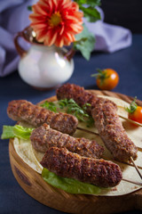 Lamb kebabs on serving board with pita bread, vegetables and yogurt sauce.