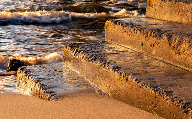 Old concrete steps sprinkled with sand and washed by sea waves