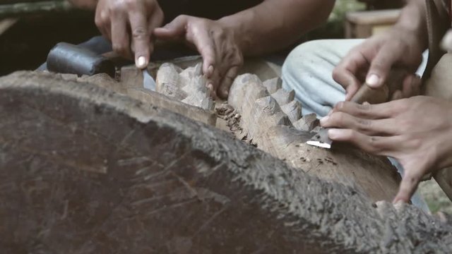 Pan to a wood carver who is carving. Pan to a wood carver who is carving leaves with chisel