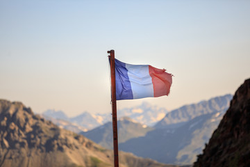 The flag of France flutters in the blue sky against the backdrop of the mountains. Theme of nature.