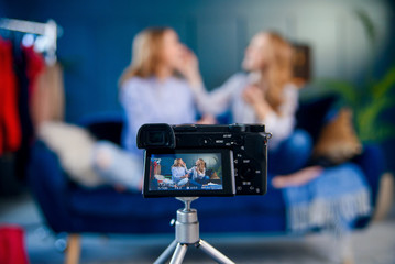 Close up shot of professional camera during shooting two attractive blogger recording beauty video.