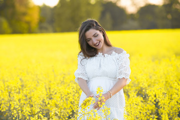 Fototapeta premium Pregnant girl on a yellow background. looks at his stomach, imagines his unborn child. Maternity concept