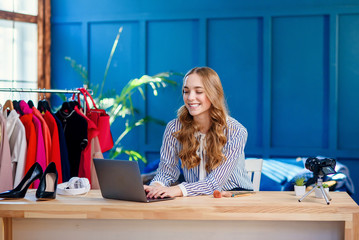 Attractive female blogger using laptop in the blue room
