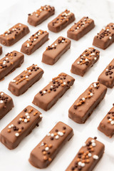 Exclusive handcrafted chocolate candy. Luxury handmade bonbon decorated with popped rice on white marble background. Product concept for chocolatier
