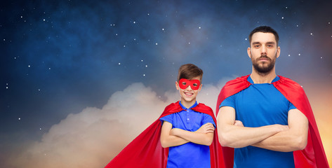 super family, power and fatherhood concept - father and son in red superhero cape over night sky...