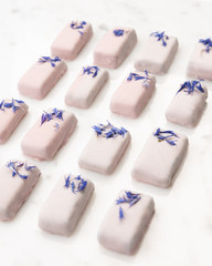 Exclusive handcrafted purple chocolate candy. Luxury handmade bonbon decorated with lavender on white marble background. Product concept for chocolatier