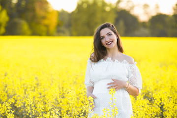 Pregnant girl on the rapeseed field. cute young woman waiting a baby