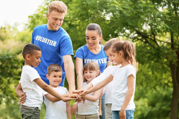 Group of kids joining hands with volunteers in park