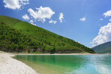 Bright rich green mountain slopes on the shore of lake Kezenoi Am. The Botlikh district in Dagestan. Sunny day