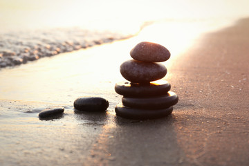 Dark stones on sand near sea at sunset, space for text. Zen concept