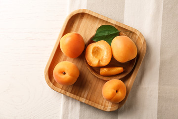 Plates with delicious apricots on white wooden background, top view