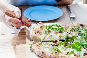 Girl holding pizza slice. pizza with cheese, pineapple, chicken and vegetables.