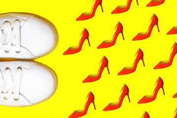Fashion white sneakers against female red shoes pattern on bright yellow background. Party, Valentine's Day, Christmas, Happy New Year, Black Friday, wedding outfit conception. Flat lay, top view.