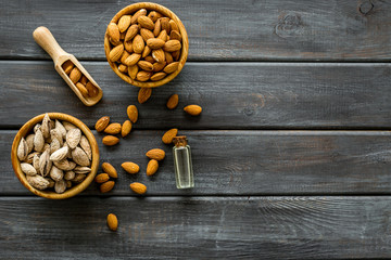 Almond oil in bottle with almonds on wooden background top view copyspace