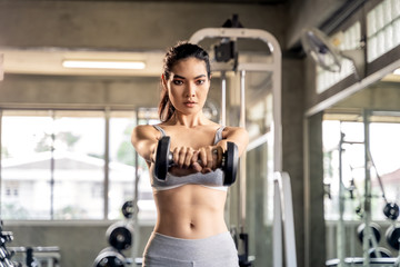 Obraz na płótnie Canvas Asian beautiful woman is lifting double in the gym, She smile happily in exercise because it makes her shapely, the concept of exercise, lose weight, strengthen muscles.