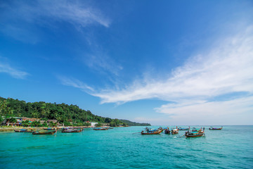 Traditional Thai fishing boats wrapped with colored ribbons. Against the backdrop of a tropical island