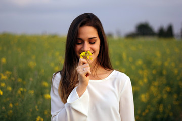 Fototapeta premium Women smelling yellow flower in yellow flowers field