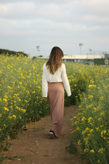 Fototapeta premium Beautiful woman on yellow flowers field with dark cloudy sky