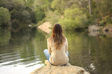 Woman sitting on a rock near the lake