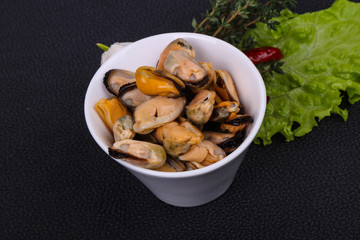 Pickled mussels in the bowl served pepper, garlic and salad