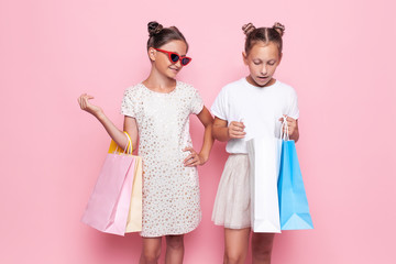 Two smiling teenage girls hold bags in their hands after a shopping trip